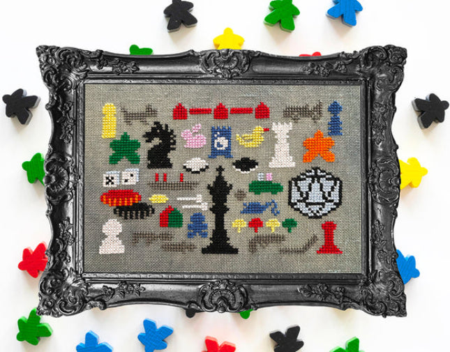 Framed cross-stitched art of chess pieces on a colorful background