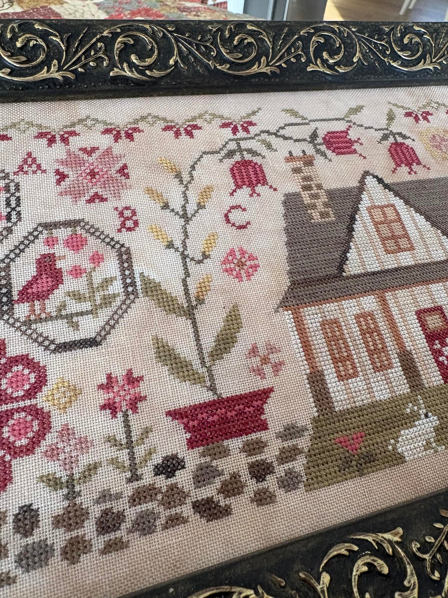 Close-up of a cross-stitched piece with floral and architectural elements.