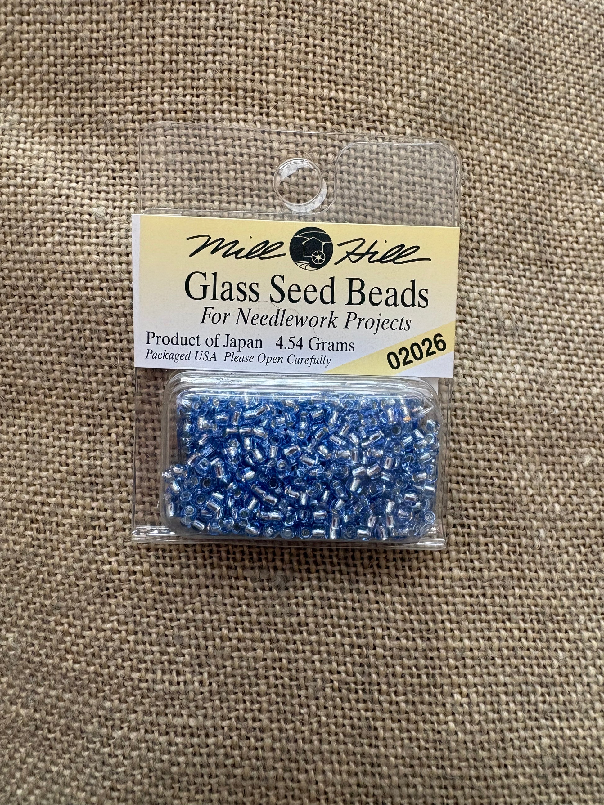Pack of blue glass seed beads with a label on a textured beige background