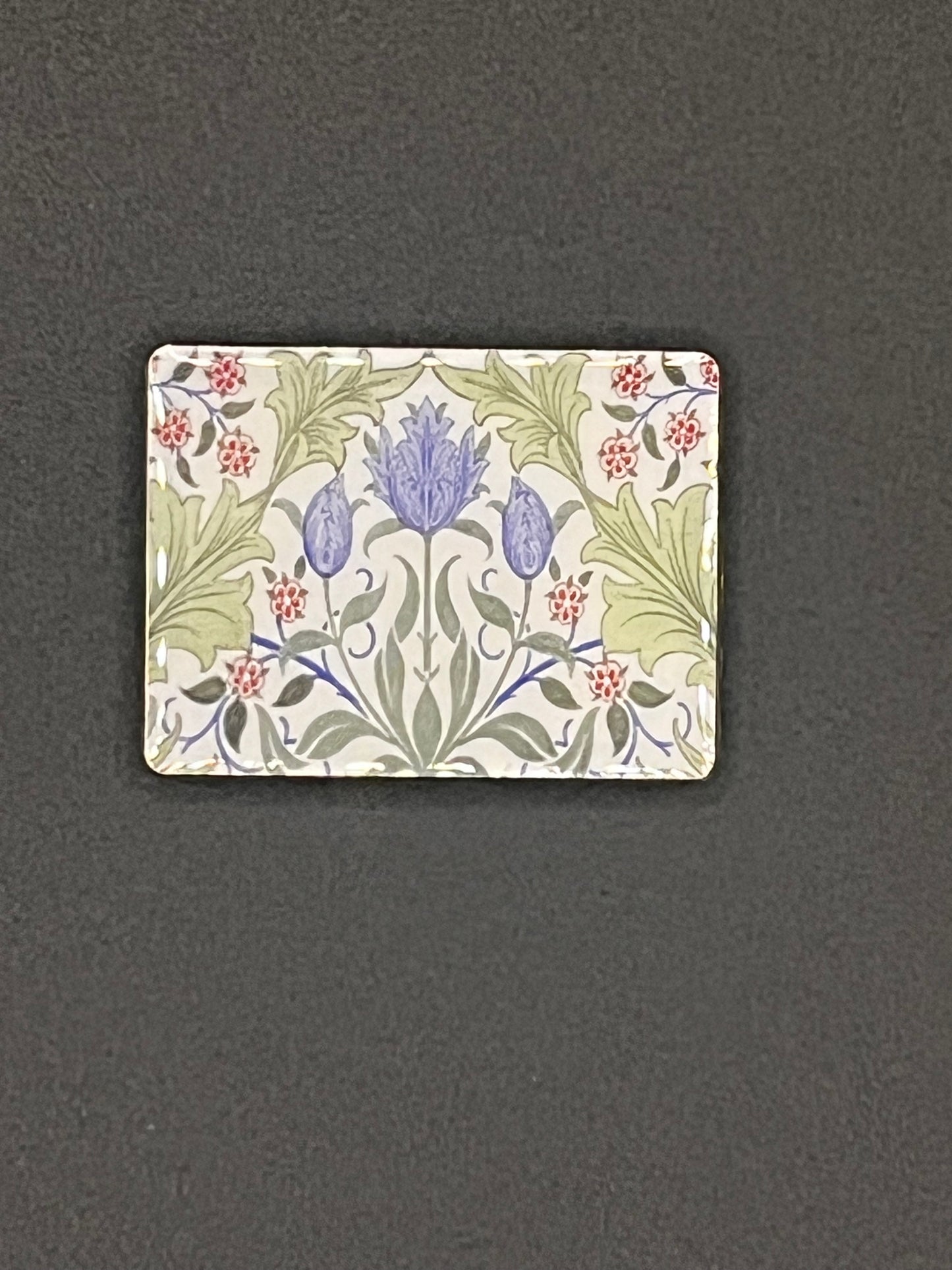 Small rectangular tile needle minder with floral design on a dark gray background
