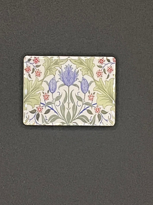 Small rectangular tile needle minder with floral design on a dark gray background