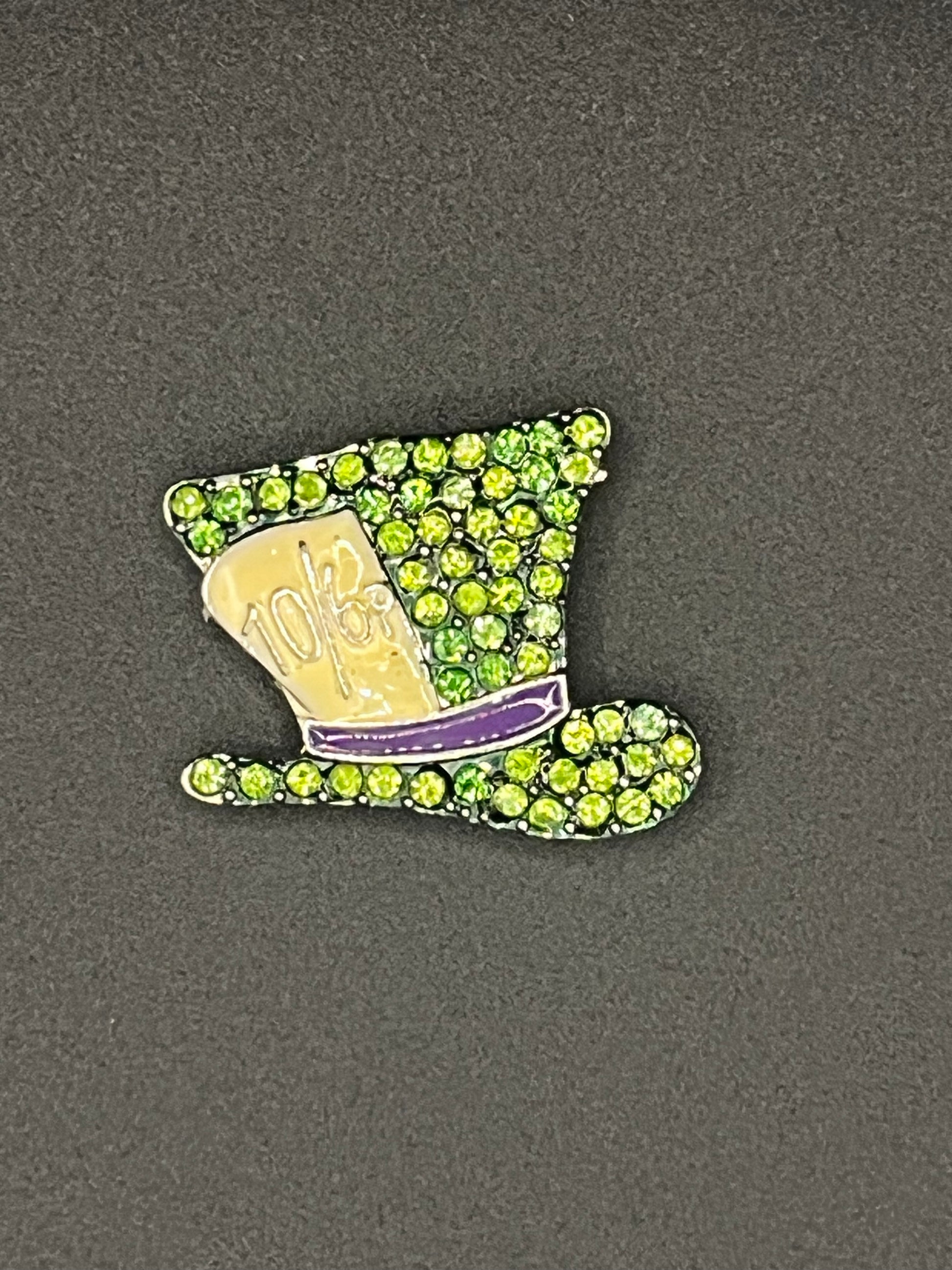 Needle minder with green gemstones on a gray background