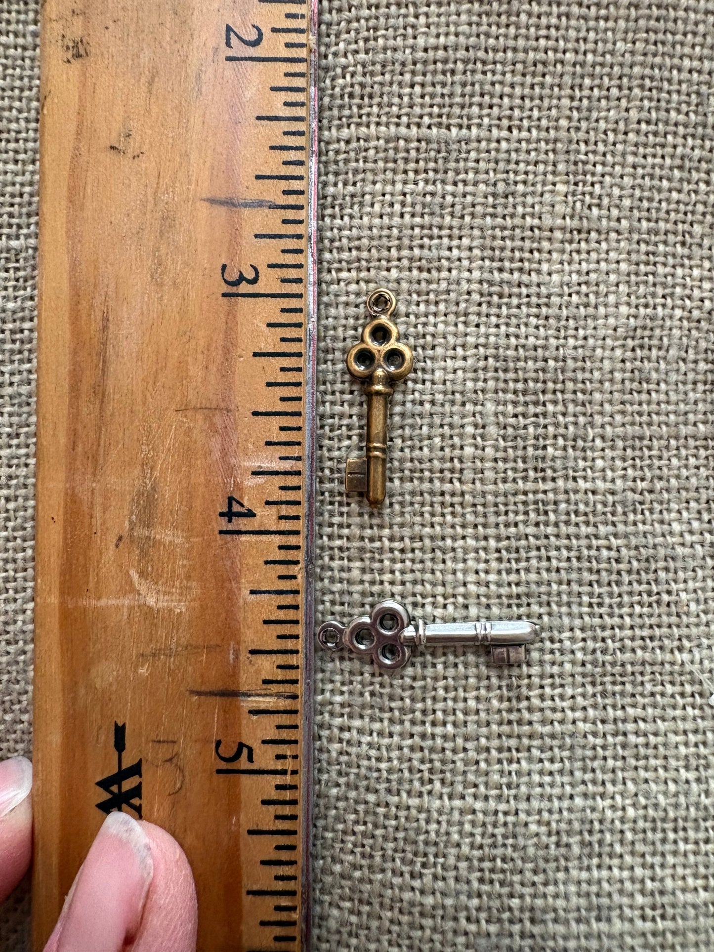 Small antique key charm next to a ruler for measurement