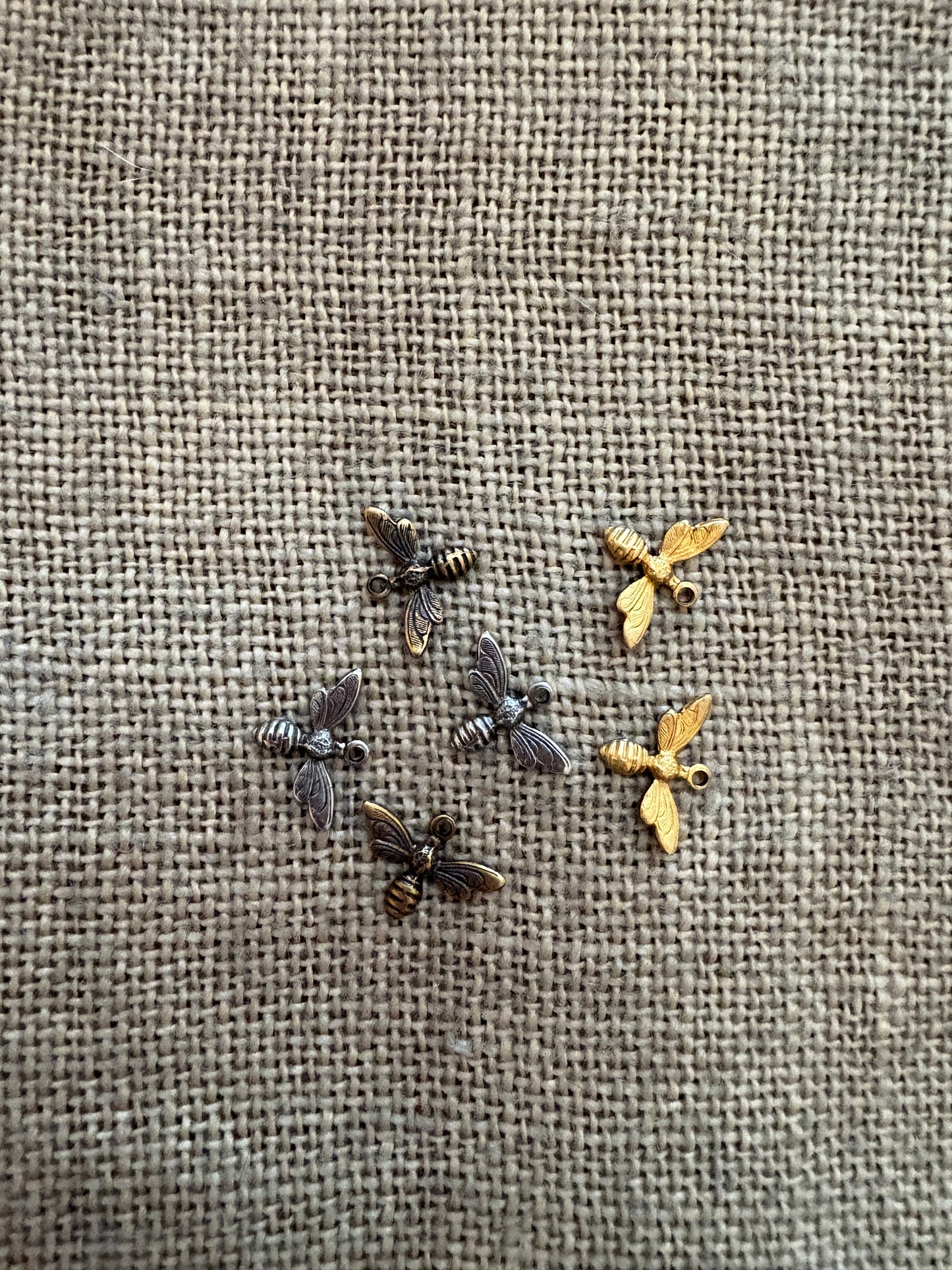 Small bee charm on a textured fabric background