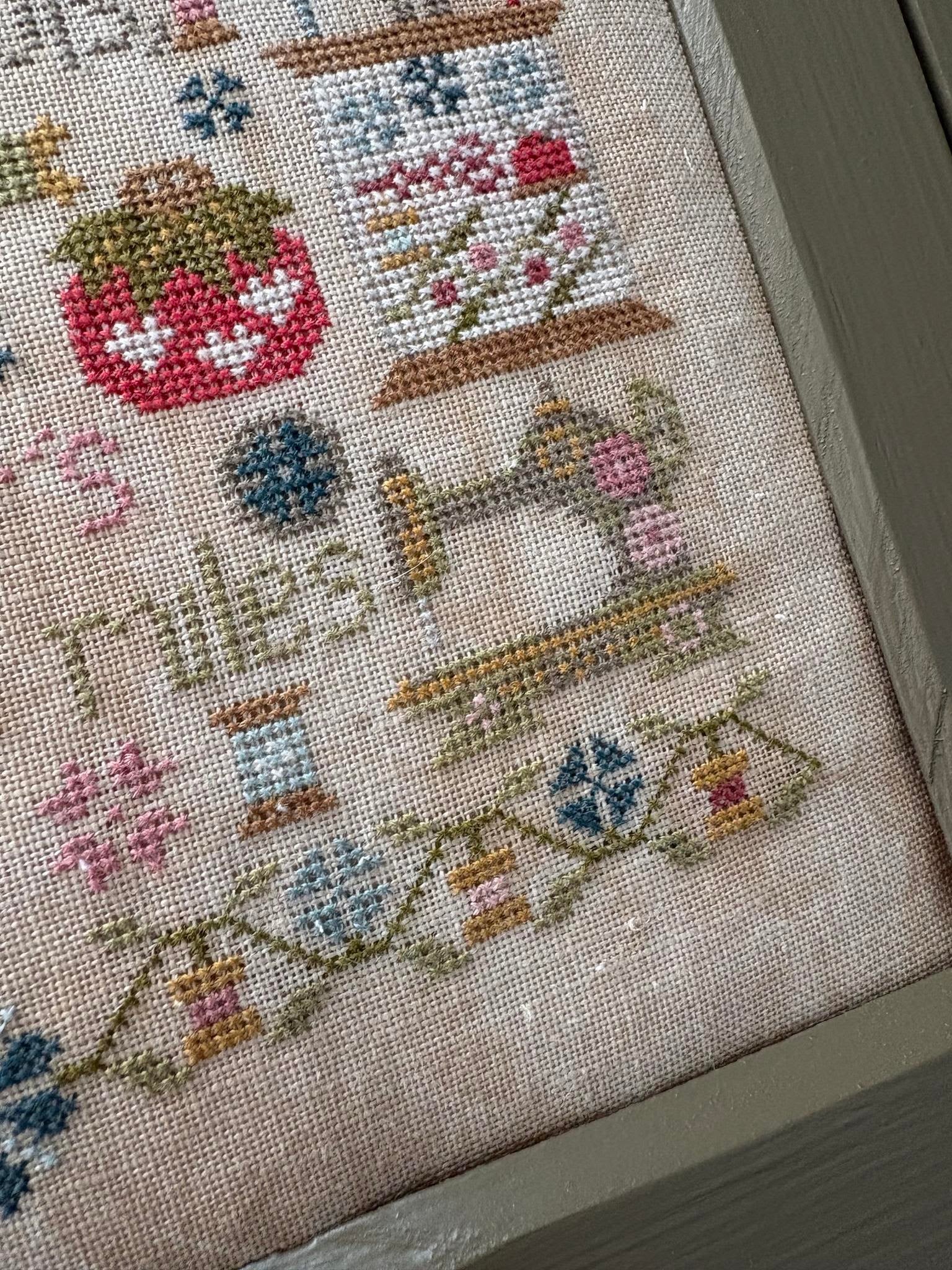 Close-up of a cross-stitched piece with various patterns and text on fabric.