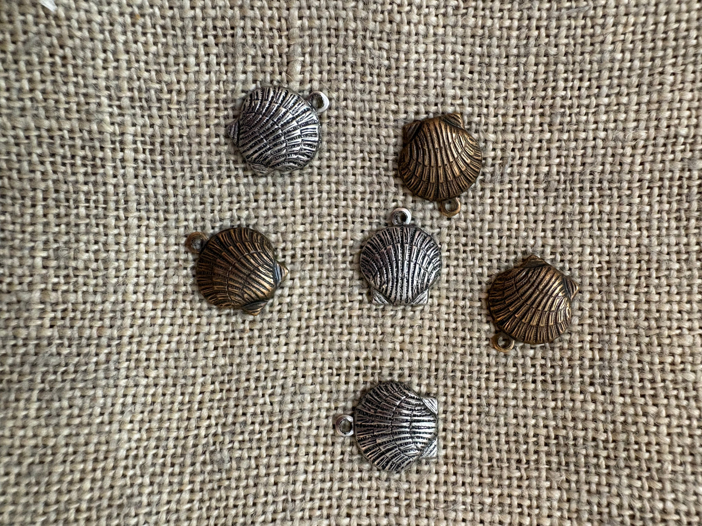 Silver shell-shaped charms on a textured fabric background