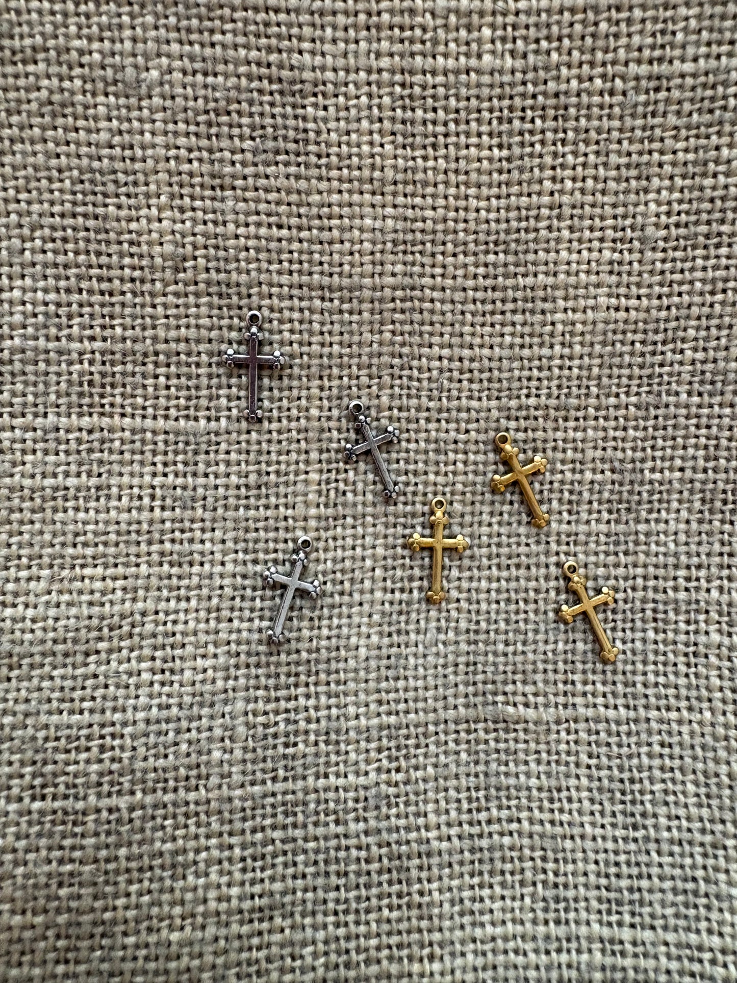 Small metal crosses on a textured fabric background