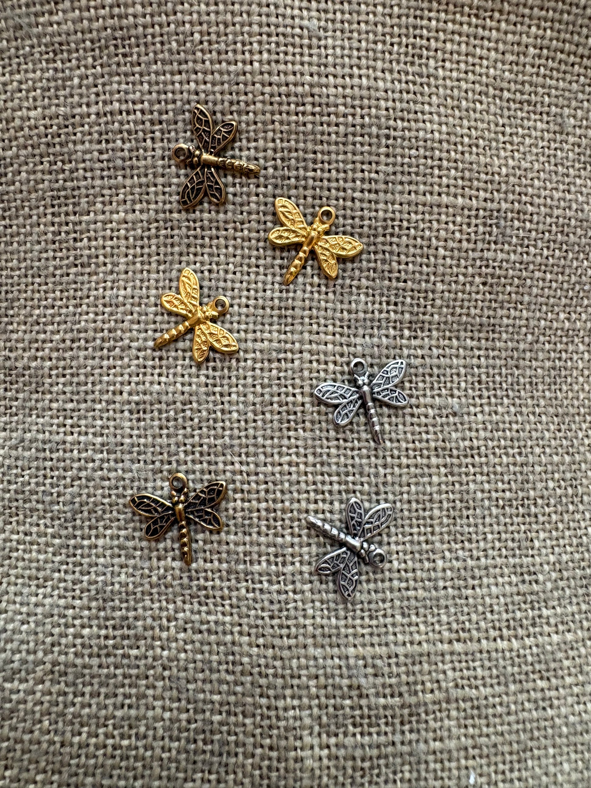 Set of dragonfly-shaped charms in 3 colors on a textured fabric background