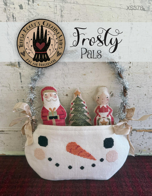 Decorative basket with knitted figures of Santa Claus, a tree, and a child, labeled 'Frosty Pals', on a rustic background.