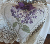 Heart-shaped embroidered piece with purple flowers on a lace background