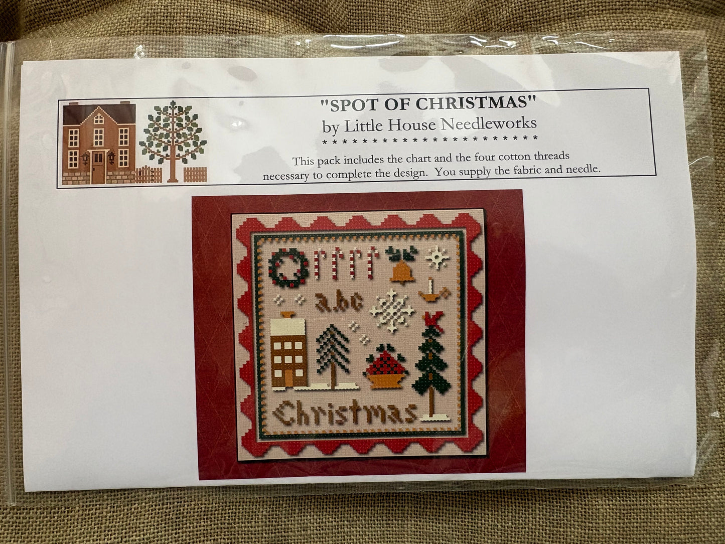 Cross-stitch kit packaging with design and branding details on a textured surface