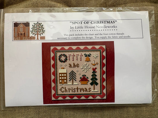 Cross-stitch kit packaging with design and branding details on a textured surface