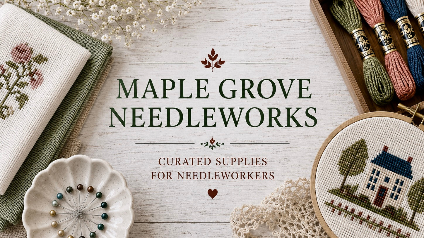 Maple Grove Needleworks advertisement with cross-stitching supplies on a wooden surface.