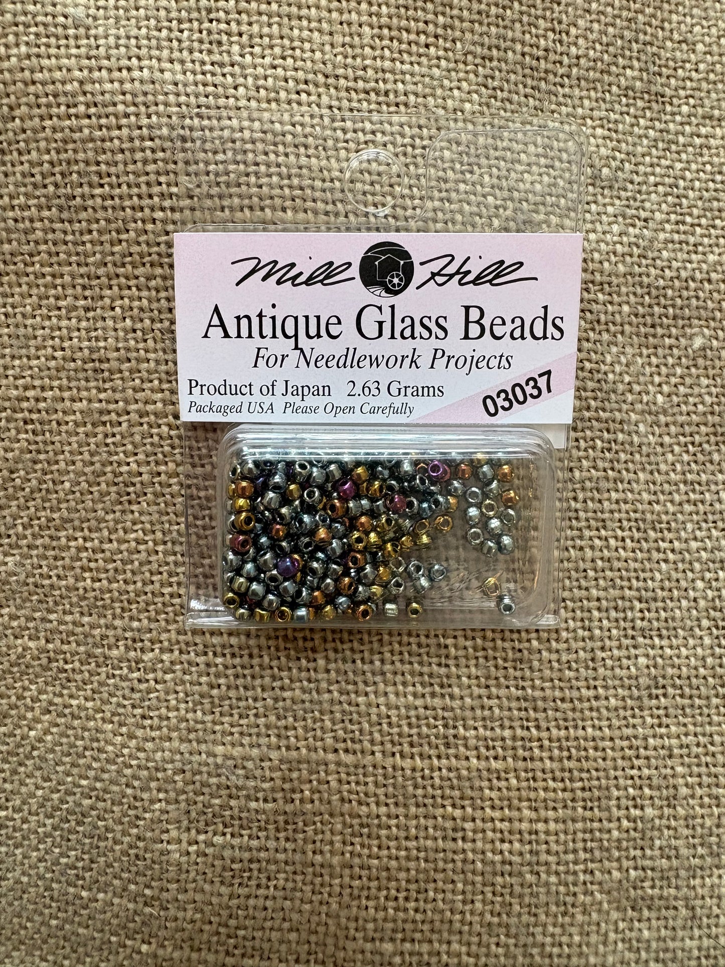 Pack of antique glass beads with a label on a textured fabric background