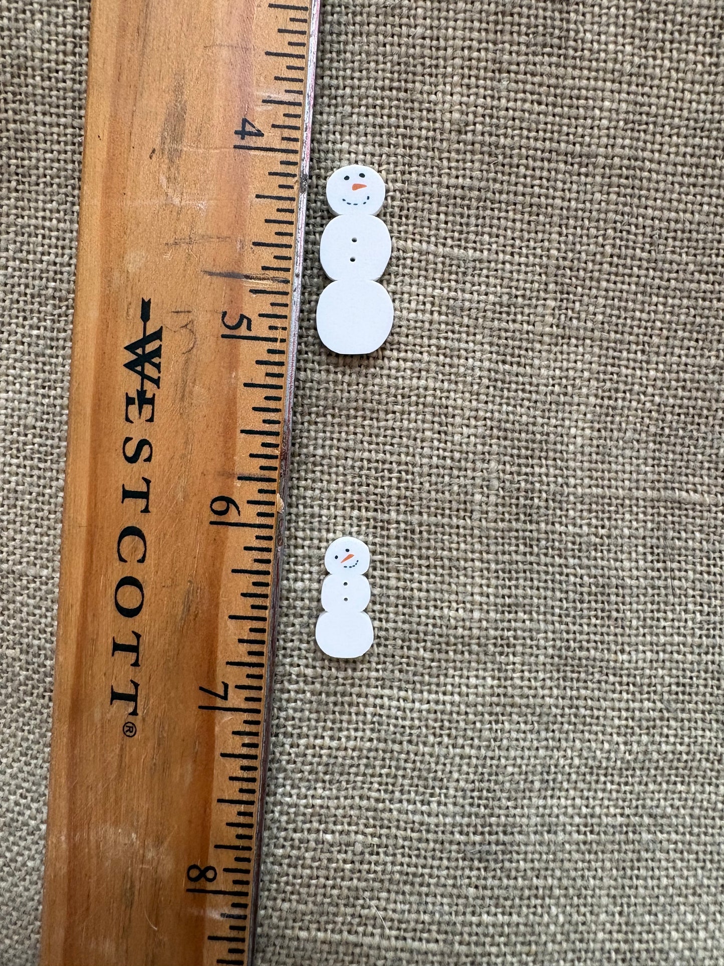 Pair of white earrings on a textured fabric background with a Westcott ruler for scale.