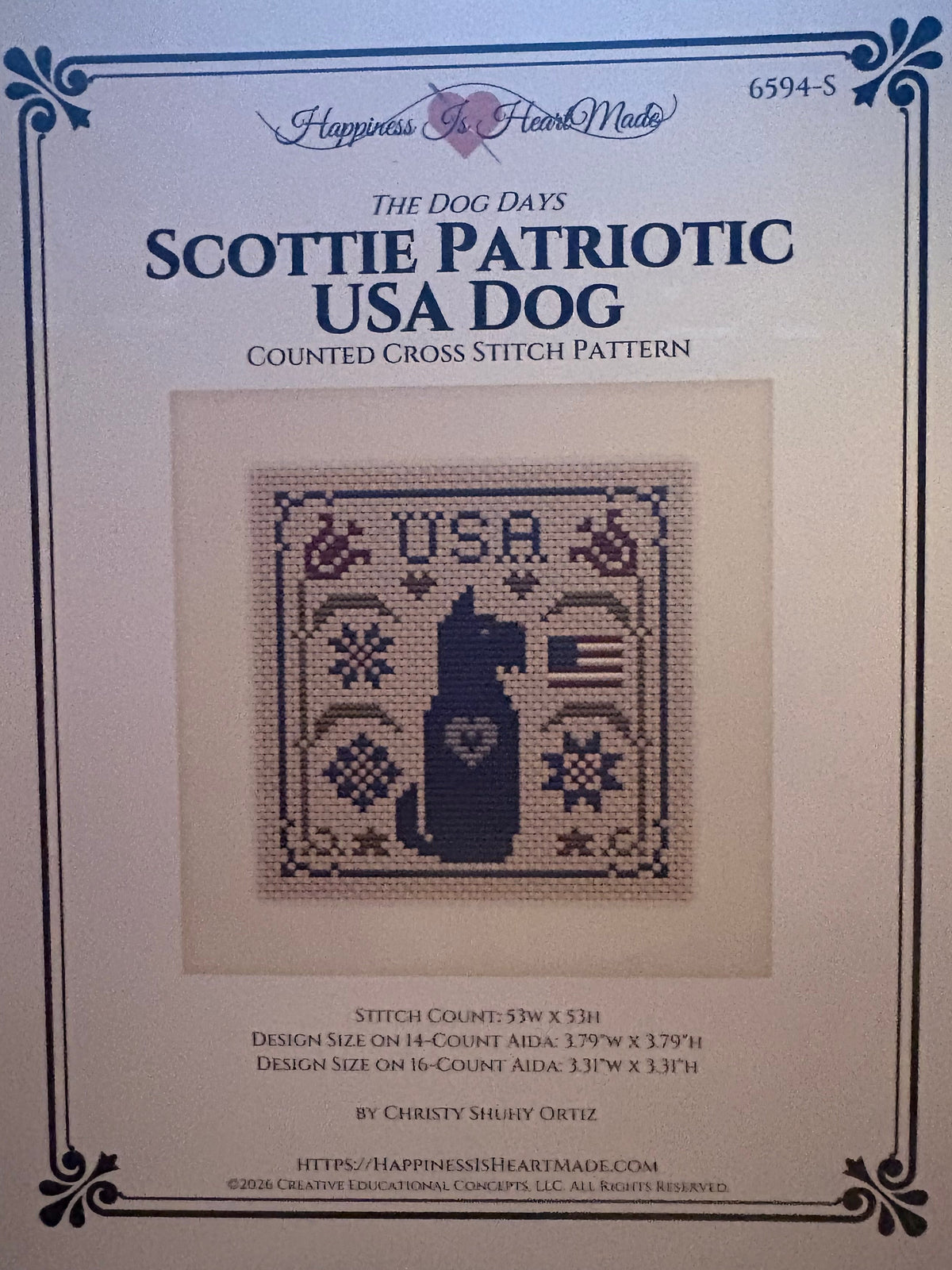 Front cover of a counted cross stitch pattern booklet titled 'The Dog Days: Scottie Patriotic USA Dog' by Happiness in a Frank Mead, showing a central stitched dog design on a cream background.