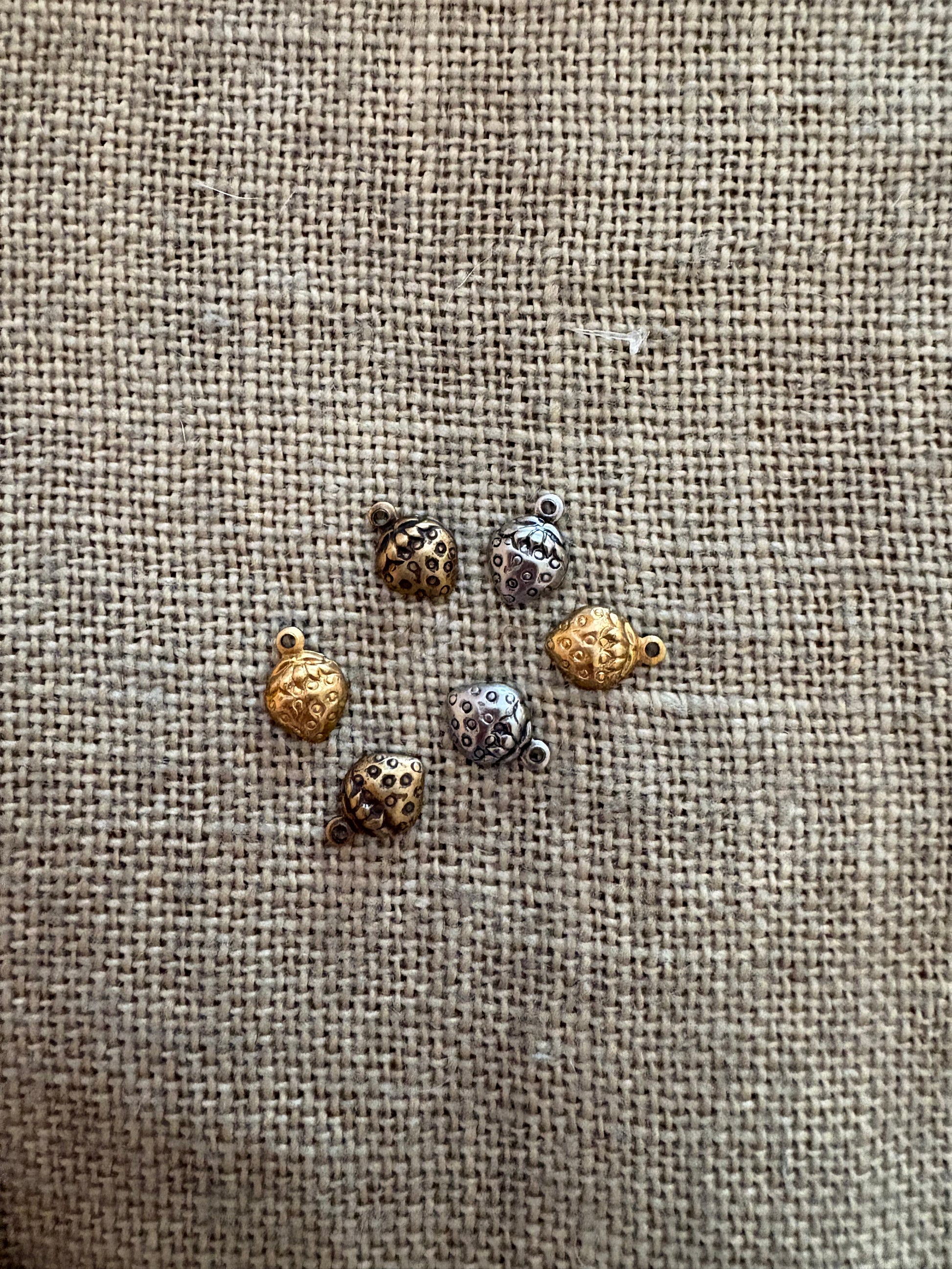 Small strawberry harms on a textured fabric background