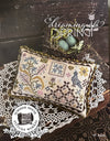 Cross-stitched pillow with decorative patterns, eggs in a nest, and 'Dreaming of Spring' text on a wooden surface.