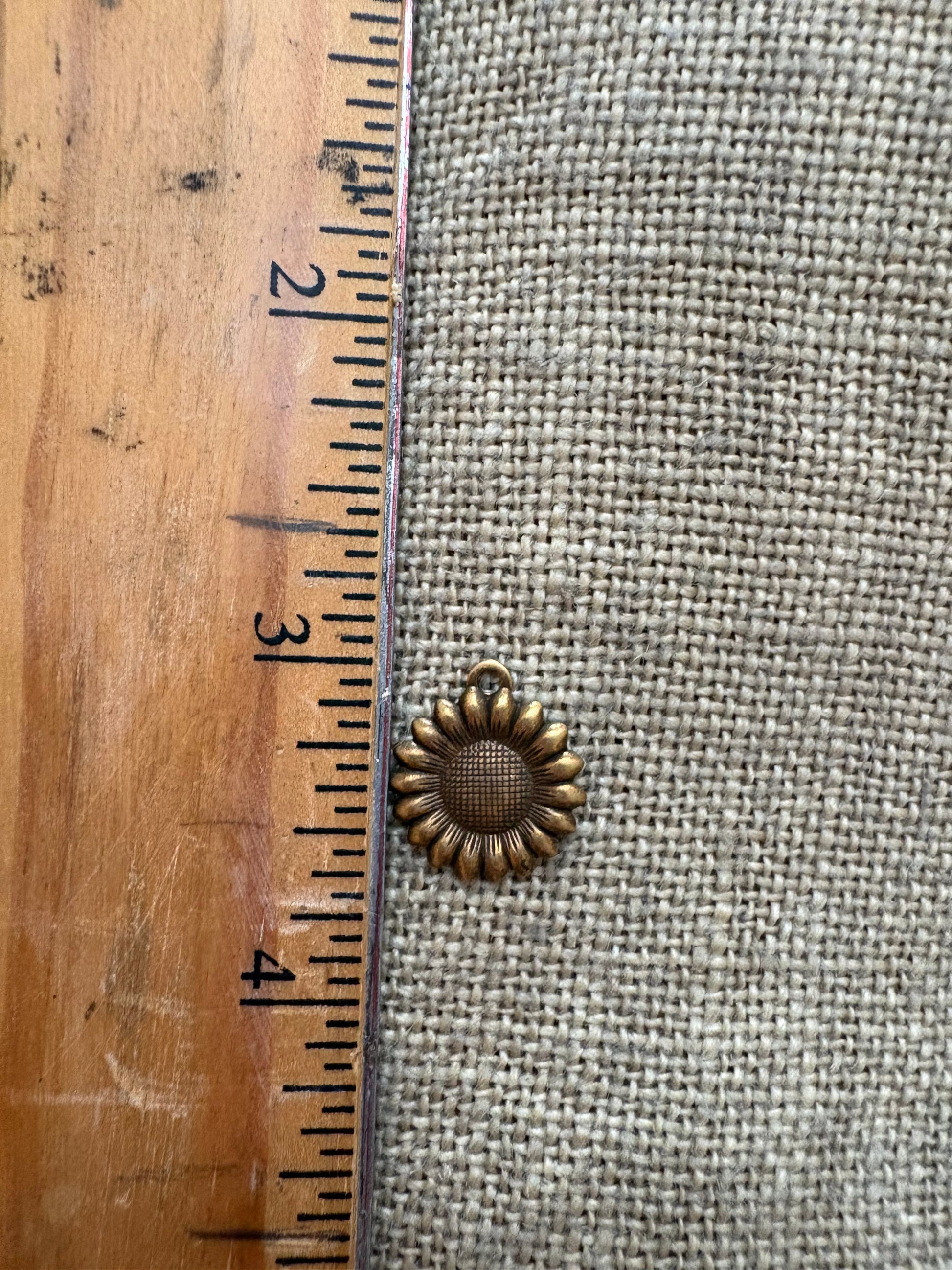 Small sunflower charm next to a rules for measurement