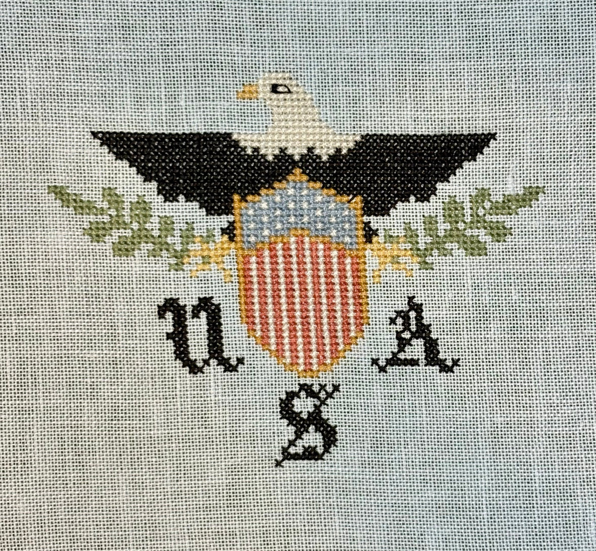 Embroidered design of an eagle with a shield and 'U.S.' text on fabric.